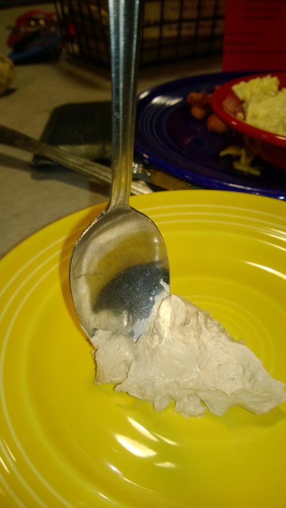 A spoon stuck upright in a smooth fluffy dessert with no other form of support.