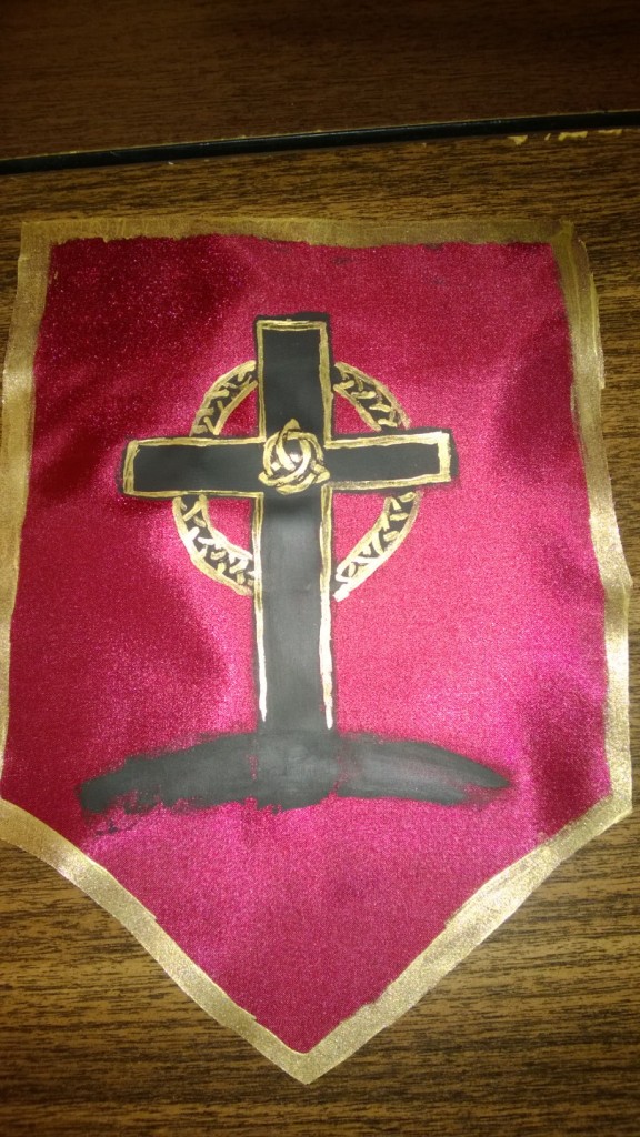 A scarlet banner with a gold rim and a black and gold painted cross