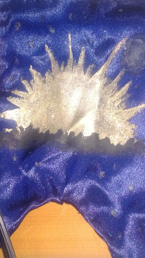 Gold painted sun on dark blue miniature banner.