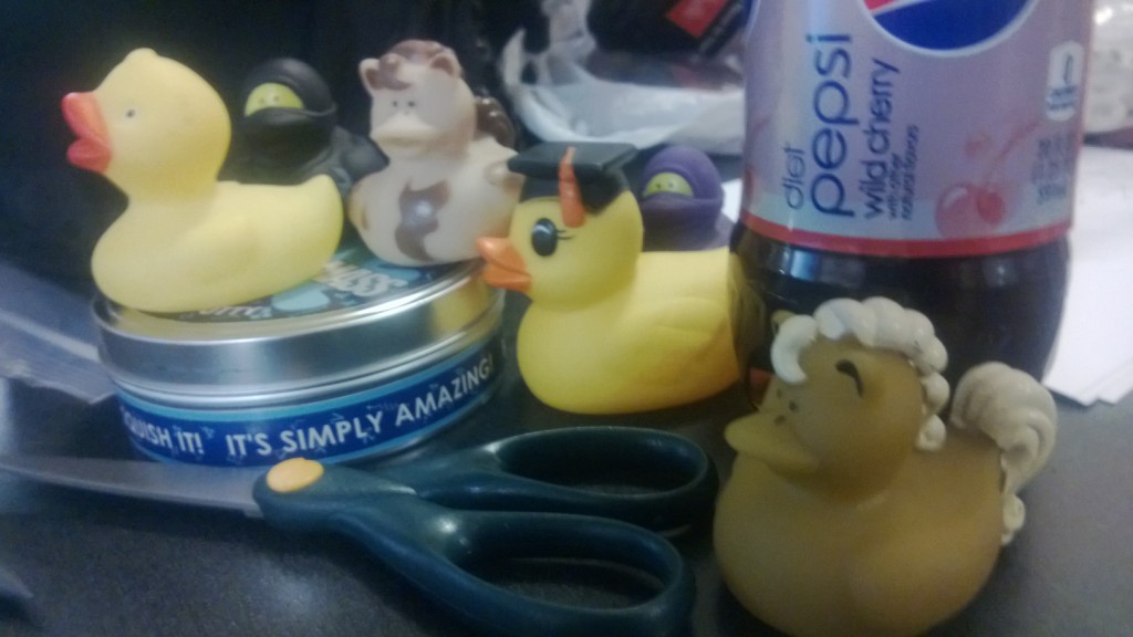 A group of rubber ducks, scissors, silly putty, and a diet beverage.
