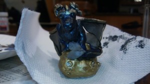 blue, gold, and black dragon on a pile of treasure.