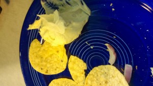 "Guacamole" of a yellowish hue with corn chips.